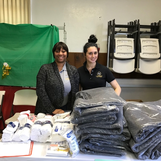 Pacific Workers' Compensation staff handing out blankets, socks, and hygiene kits.
